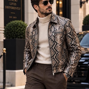 May include: A snakeskin-patterned jacket with a pointed collar and silver zip closures, worn over a cream-coloured turtleneck sweater and dark brown trousers. The jacket features a textured brown and black scale print and long sleeves.