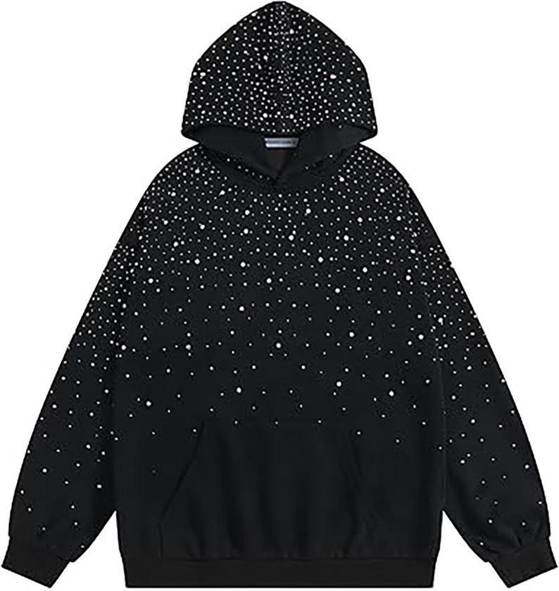 May include: Black hoodie with a white dot pattern, featuring a hood and a front pocket. The white dots are densely packed at the top and gradually fade towards the bottom. The hoodie is made of a soft material.