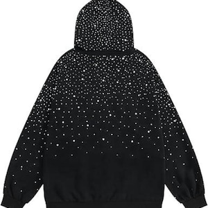 May include: Black hoodie with a white dot pattern that fades from the hood down. The hoodie has a drawstring hood, long sleeves, and a ribbed hem and cuffs. The design gives the appearance of a starry night sky.