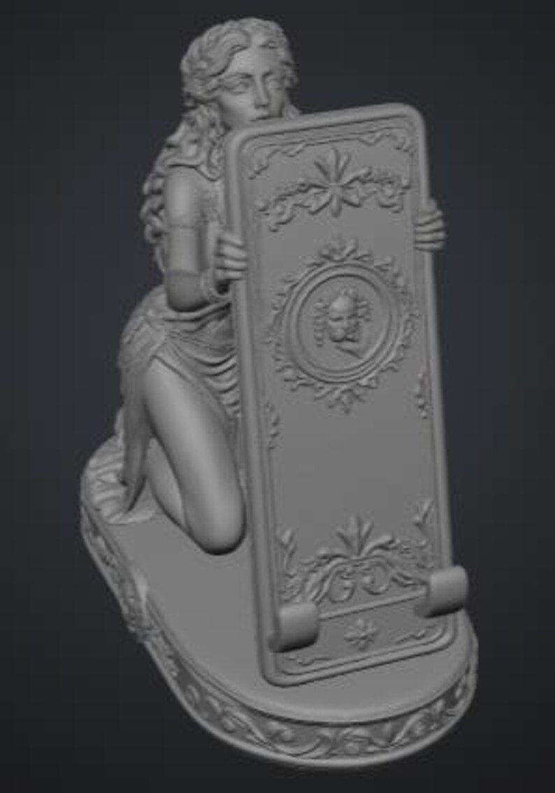May include: A gray monochromatic sculpture of a kneeling figure with long wavy hair holding a rectangular tablet. The tablet features a central circular relief of a cherub face, ornate floral carvings, and two small curved supports at the base.