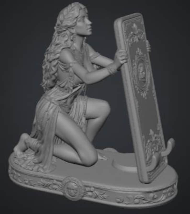 May include: A gray resin figurine of a kneeling figure with long flowing hair, wearing a draped garment and jewelry. The figure holds a tall, rectangular, ornate frame with a central circular emblem, all set upon an oval base with floral carvings.