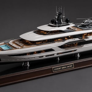 Puede incluir: Una maqueta detallada de un megayate blanco y negro con varias cubiertas, una piscina en la proa y un helicóptero en la plataforma de aterrizaje trasera. El modelo está montado sobre una base de madera oscura con la placa LUXURY MEGA YACHT.