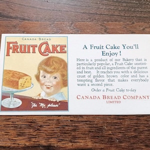 May include: A vintage advertisement for Canada Bread Fruit Cake. The image shows a child and a slice of fruitcake. Text includes "Fruit Cake" and "For Me please."