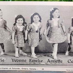 May include: A vintage black and white photograph featuring the Dionne quintuplets. The five girls are dressed alike in dresses with pleated skirts, white socks, and shoes. Each girl has a bow in her hair. The names Marie, Yvonne, Emelie, Annette, and Cecile are printed below.