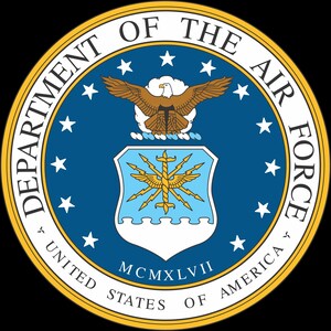 Puede incluir: El emblema oficial de la Fuerza Aérea de los Estados Unidos, con un escudo central con un diseño estilizado, rodeado por un círculo azul con estrellas blancas y texto. El emblema incluye un águila dorada y los textos "DEPARTMENT OF THE AIR FORCE" y "UNITED STATES OF AMERICA".