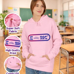 Puede incluir: Una sudadera con capucha rosa claro con un bolsillo delantero y una capucha con cordón. La sudadera con capucha presenta un gráfico en la parte delantera con el texto "E Energy MC". Las palabras "Cute Pink Hoodie" y "Retro Aesthetic Design" están en la parte superior de la imagen.