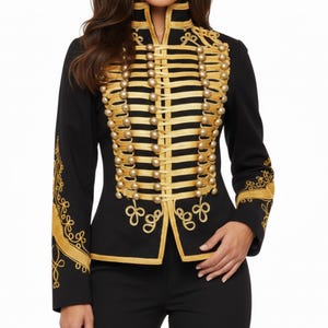 May include: Black jacket with gold military-style embellishments. The jacket features gold trim, rows of gold buttons, and decorative gold embroidery on the sleeves. The high collar and tailored fit give it a formal appearance.