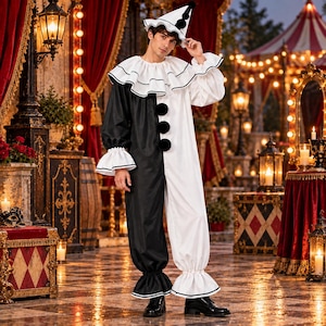 May include: A black and white clown costume featuring a long-sleeved jumpsuit with a split color design, a large ruffled collar, and three black pom-poms down the front. The outfit includes a matching cone-shaped hat with black pom-pom accents.