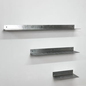 Puede incluir: Tres estantes de pared de metal en forma de L de longitudes variables, cada uno con un acabado plateado cepillado y orificios de montaje circulares preperforados a lo largo del panel trasero vertical para una instalaci&oacute;n segura.
