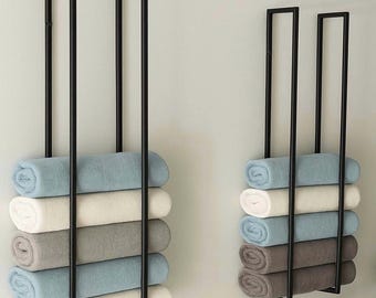 May include: Two black metal towel racks mounted on a wall, each holding six rolled towels. The towels are in shades of blue, white, and gray, creating a minimalist and organized look for a bathroom or spa.