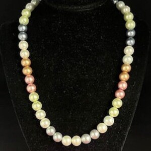 May include: A multi-colored pearl necklace with a gradient of colors from light green to pink. The necklace is made of round pearls and is approximately 18 inches long.