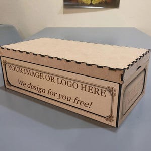 A wooden box with a lid, sitting on a table. The box has a message that says "YOUR IMAGE OR LOGO HERE We design for you free!"