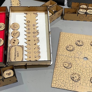 Może przedstawiać: Drewniany zestaw gier planszowych z różnymi elementami. Zawiera drewniane żetony, plansze do gry i pudełka do przechowywania. Elementy gry mają skomplikowane wzory i tekst. Zestaw przeznaczony jest do gry na stole.