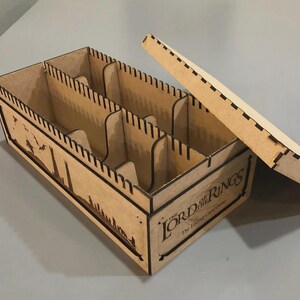 A wooden box with the Lord of the Rings logo printed on it, sitting on a gray surface.