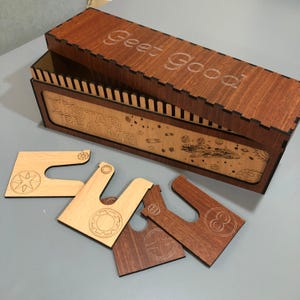 a wooden box with the phrase "Goet Good" written on it, along with various wooden pieces, including a piece with a star and a piece with a circle.