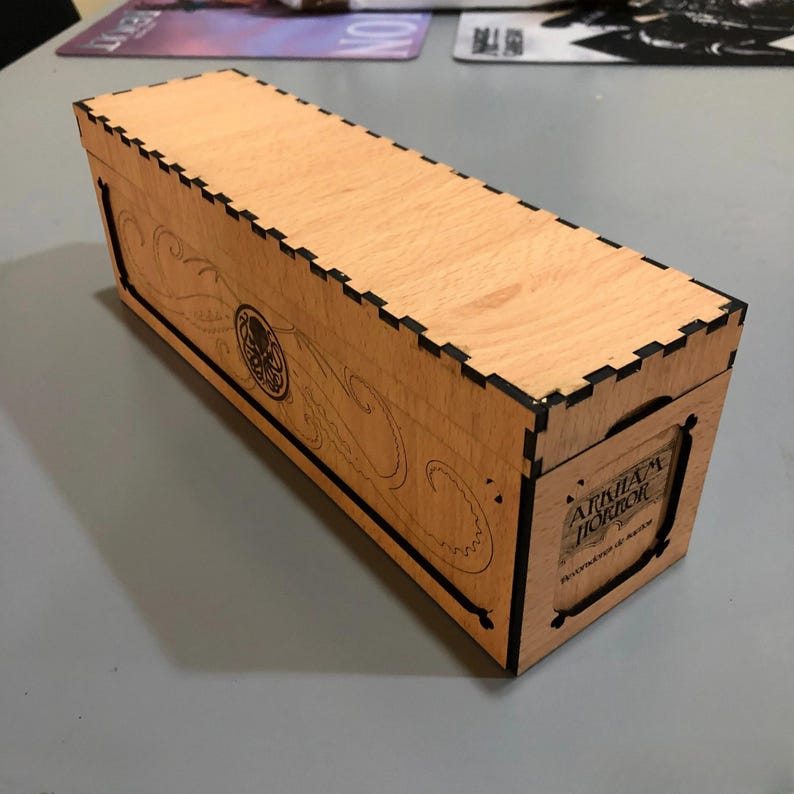 A wooden box with a lid, featuring a design and text on the front.