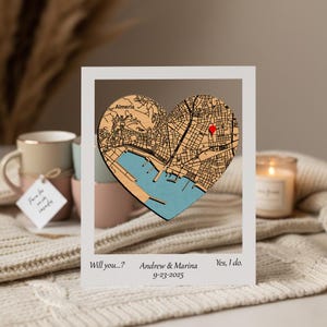 Puede incluir: Un mapa de madera en forma de corazón de Almería, España, con un alfiler rojo. El mapa está enmarcado en un marco blanco con el texto "Will you...?", "Andrew & Marina 9-23-2025" y "Yes, I do."