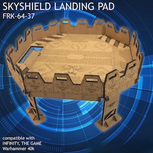 Peut inclure: Un Skyshield Landing Pad en bois découpé au laser, modèle FRK-64-37, pour les jeux de table. Le pad présente un design détaillé avec des motifs géométriques et des structures de support. Le texte "SKYSHIELD LANDING PAD" et "FRK-64-37" sont visibles.