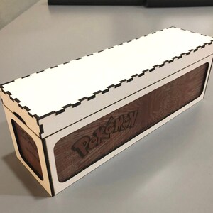 A wooden box with a white interior, featuring the Pokemon logo on the side.