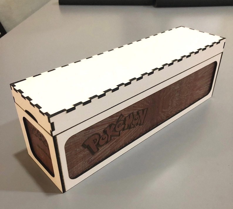A wooden box with a white interior, featuring the Pokemon logo on the side.