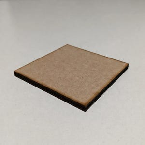 May include: A square, wooden coaster with a light brown surface and dark brown edges. The coaster is made of a composite material and is designed to protect surfaces from heat and moisture.