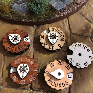 Op de afbeelding: Houten wondentellers met een cirkelvormig ontwerp. Elke teller heeft een draaischijf met cijfers van 0 tot 30 en een centraal embleem. De tellers zijn ontworpen voor tabletop gaming.