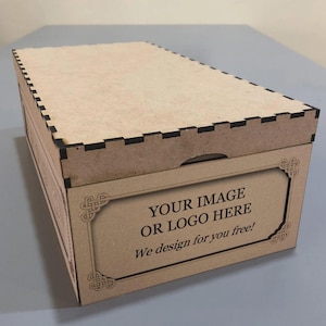May include: A rectangular wooden box with a lid, featuring a decorative frame on the front panel. The box has a natural wood color with black accents along the edges. Text on the front reads "YOUR IMAGE OR LOGO HERE" and "We design for you free!"