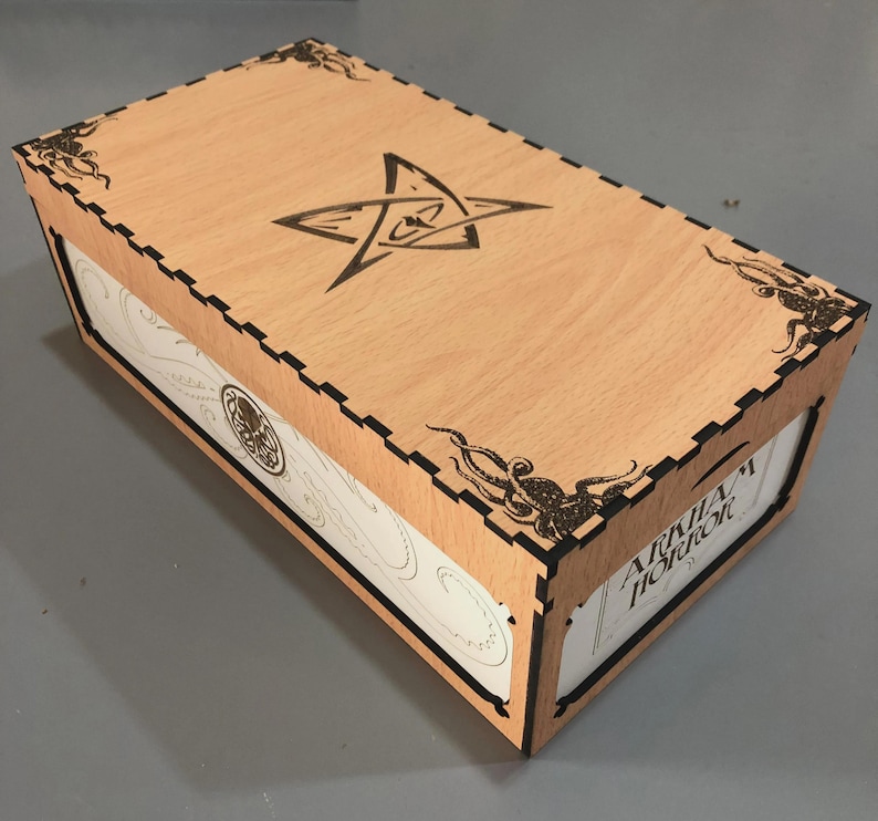 A wooden box with a star-shaped emblem on the lid, featuring intricate designs and patterns around the edges.