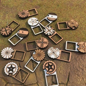 Puede incluir: Un conjunto de fichas de juego de madera con varios diseños, incluyendo estrellas, cruces y patrones de banderas. Cada ficha tiene un dial circular y un marco rectangular. Las fichas son principalmente marrones, blancas y negras, dispersas sobre una superficie texturizada.
