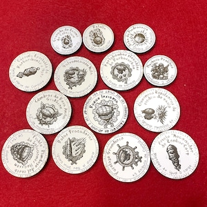 Puede incluir: Colección de fichas circulares con ilustraciones y texto en blanco y negro. Las fichas presentan varios diseños, incluyendo un barco, una bomba y una calavera. El texto está en español.