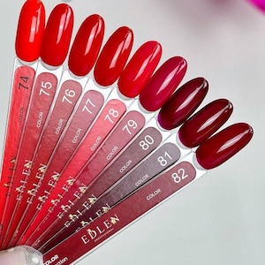 Puede incluir: Muestras de esmalte de uñas rojo, numeradas del 74 al 82. Los tonos varían del rojo brillante al burdeos oscuro. La marca "EDLEN PROFESSIONAL" es visible en las varillas. También se ven las palabras "COLOR Collection".