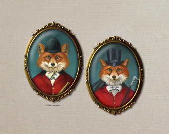 May include: Two oval-shaped brooches with gold-toned frames and glass insets. Each brooch features a fox wearing a red hunting jacket and a hat. One fox wears a top hat and the other wears a riding helmet. Both foxes have a white bow tie and a whip.
