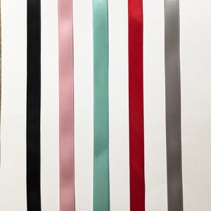 Peut inclure: Assortiment de six bobines de ruban satin&eacute; de diff&eacute;rentes couleurs, dont noir, rose, bleu clair, rouge et gris.