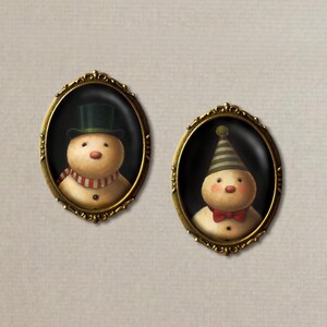 以下が含まれることがあります： 雪だるまの肖像画が描かれた、楕円形の額縁が2つ。左側の雪だるまは緑色のシルクハットと赤と白のストライプのストールを着用しています。右側の雪だるまは緑と白のストライプの帽子と赤い蝶ネクタイを着用しています。両方の雪だるまは黒い目と赤い頬をしています。