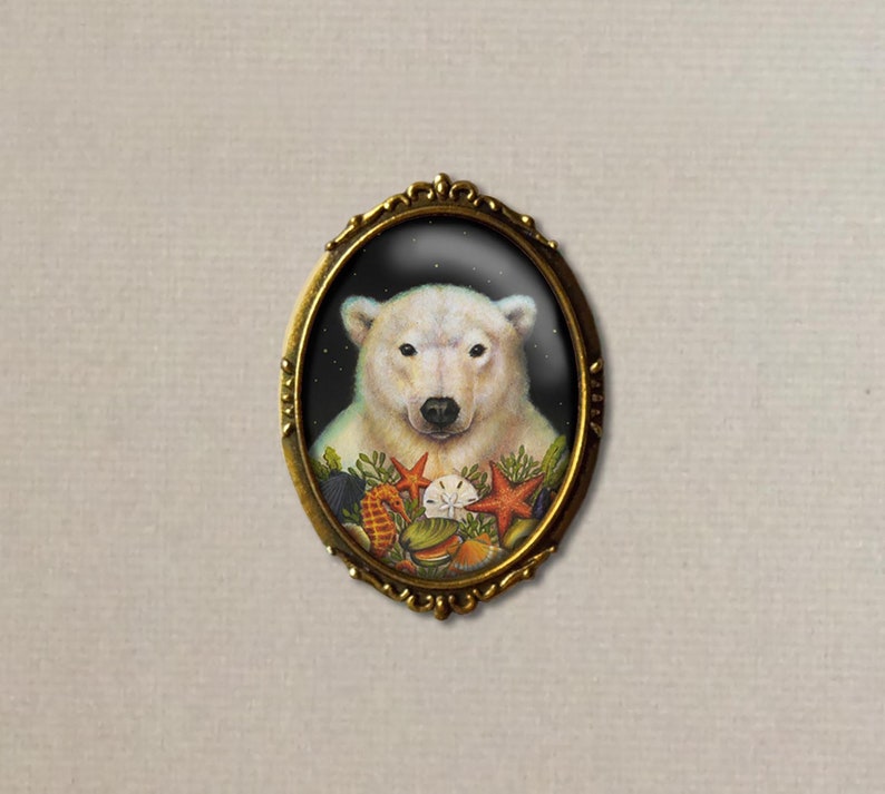 May include: A white polar bear with a black nose and eyes is surrounded by seashells and starfish in a gold oval frame. The background is a dark blue.