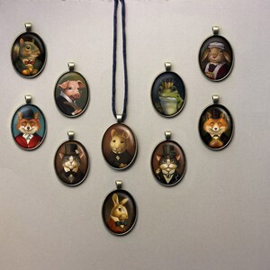 May include: A collection of 10 oval-shaped pendants featuring various animals wearing hats and bowties. The pendants are made of metal and have a vintage aesthetic. The animals include a squirrel, pig, frog, fox, cat, and rabbit.
