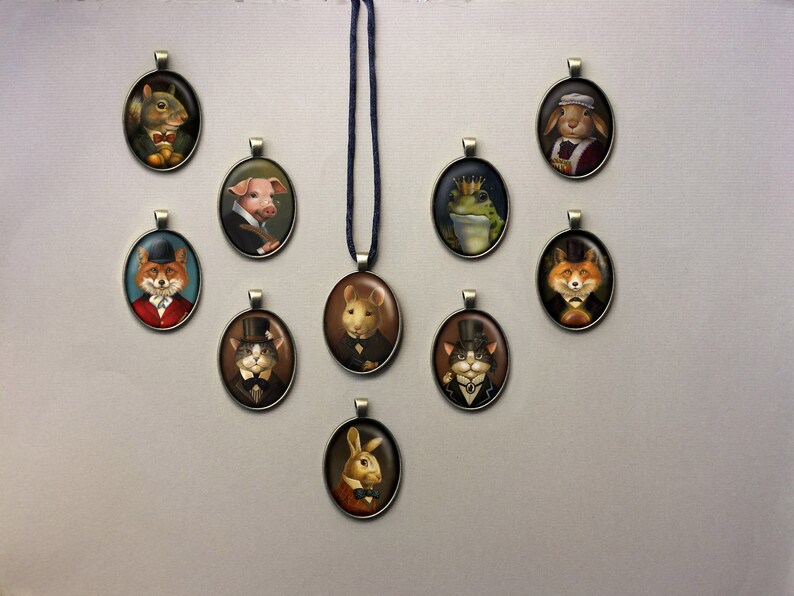 May include: A collection of 10 oval-shaped pendants featuring various animals wearing hats and bowties. The pendants are made of metal and have a vintage aesthetic. The animals include a squirrel, pig, frog, fox, cat, and rabbit.