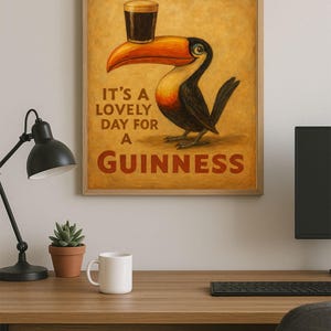 May include: A framed print featuring a toucan with a pint of Guinness balanced on its beak. The print has the words "Guinness" and "It's a lovely day for a Guinness" in red lettering. The background is a warm, golden color.