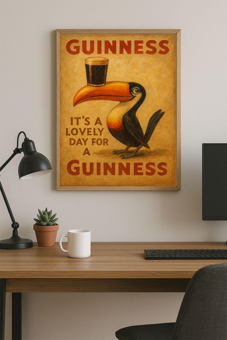 May include: A framed print featuring a toucan with a pint of Guinness balanced on its beak. The print has the words "Guinness" and "It's a lovely day for a Guinness" in red lettering. The background is a warm, golden color.