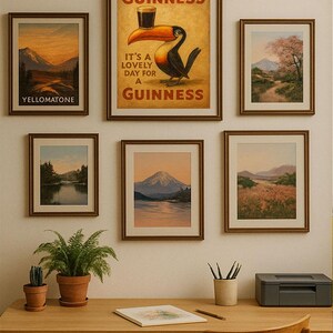 May include: A collection of framed art prints and a Guinness advertisement adorn a wall above a wooden desk. The prints depict landscapes, including mountains and a river. A Guinness poster features a toucan with a pint.