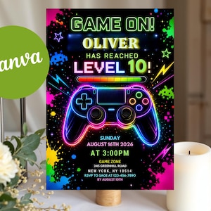 May include: A rectangular birthday invitation card with a black background featuring neon-colored graphics of a video game controller, paint splatters, and stars. The text reads: GAME ON! OLIVER HAS REACHED LEVEL 10! SUNDAY AUGUST 16TH 2026 AT 3:00PM.