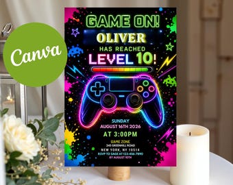 May include: A rectangular birthday invitation card with a black background featuring neon-colored graphics of a video game controller, paint splatters, and stars. The text reads: GAME ON! OLIVER HAS REACHED LEVEL 10! SUNDAY AUGUST 16TH 2026 AT 3:00PM.