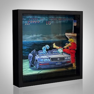 May include: A framed 3D artwork showing a scene from a classic video game. The artwork features a character in a red gi kicking a car, with text at the top. The background shows a seascape.