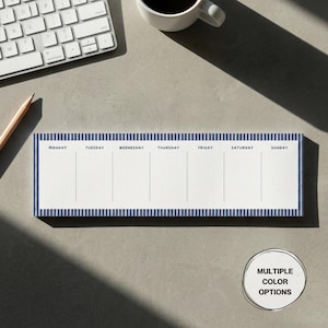 Könnte beinhalten: Wochenplaner-Notizblock mit weißem Hintergrund und blau gestreiften Rändern. Die Wochentage sind oben aufgedruckt. Ein Bleistift, eine Tastatur und eine Kaffeetasse befinden sich im Hintergrund. Der Notizblock hat mehrere Farboptionen.