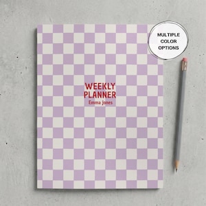Op de afbeelding: Een rechthoekige weekplanner met een lichtpaars en wit geblokt patroon. In het midden staat de tekst "WEEKLY PLANNER" en "Emma Jones" in donkerrood. Een grijs potlood ligt aan de rechterkant en een rond label vermeldt "MULTIPLE COLOR OPTIONS".