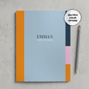 Puede incluir: Una agenda semanal rectangular con cubierta azul claro que presenta el texto EMMA'S WEEKLY PLANNER en azul oscuro. El lado izquierdo tiene una franja vertical naranja y el lado derecho muestra bloques apilados en azul oscuro, rosa y naranja. Se incluye un lápiz gris.