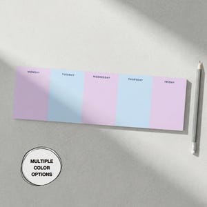 May include: A rectangular weekly planner notepad featuring alternating vertical columns in light purple and light blue. The days Monday through Friday are printed in black text at the top of each column. A gray pencil is positioned to the right.