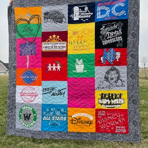 May include: A colorful quilt made from t-shirts with various designs and text. The quilt is made up of 16 squares, each with a different design. Some of the designs include "Lights Hollywood Action!" , "A Mystery at Mimsley Manor", "MDS hello summer!", "Legends Divas Superstars", "Break Away", "All Stars 2014", "Disney", and "Disney World! Spring 2019".