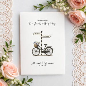 May include: A wedding card with the text "Congratulations On Your Wedding Day". The card features a black and white signpost pointing to Dublin and Galway, with a bicycle carrying a basket of flowers. The names Michael & Siobhan and the date June 20, 2025 are also printed.