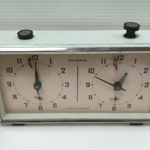 Può includere: Orologio da scacchi vintage verde chiaro con due quadranti, lancette nere e manopole nere sulla parte superiore. Il quadrante ha numeri neri e la parola "Iantar" è stampata. L'orologio è contrassegnato "MADE IN USSR".